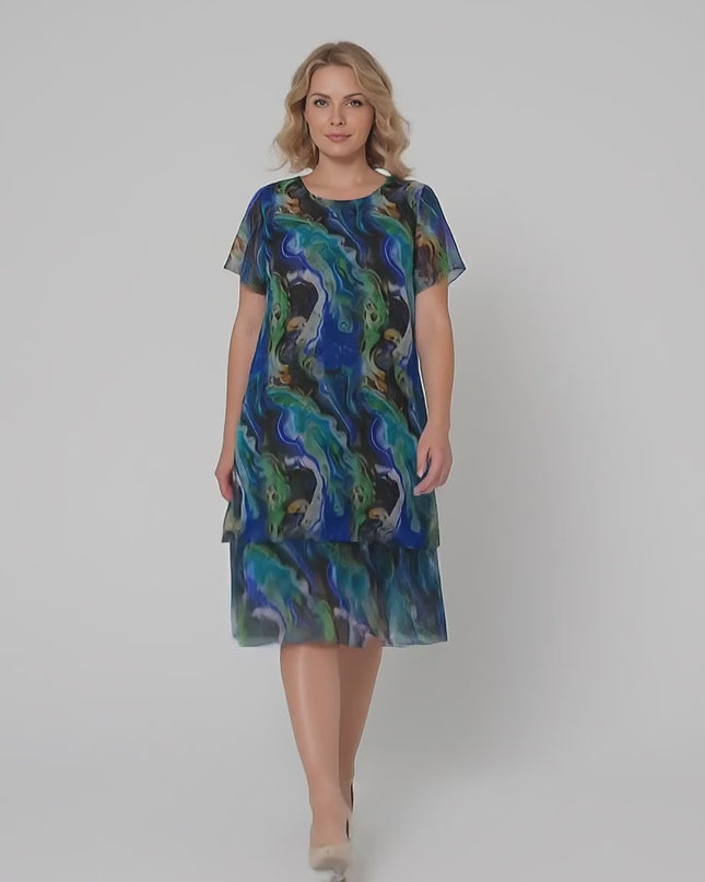 Γυναικείο μοντέλο plus size περπατάει αργά προς την κάμερα σε περιβάλλον στούντιο με ουδέτερο φόντο φορώντας το προϊόν Επίσημο σιφόν φόρεμα σε ντεγκραντέ αποχρώσεις μεγάλα μεγέθη