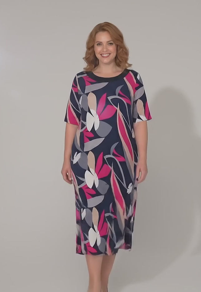 Ένα plus-size μοντέλο περπατάει αργά προς την κάμερα σε περιβάλλον στούντιο με ουδέτερο φόντο φορώντας το Επίσημο σκούρο μπλε φλοράλ μάξι φόρεμα σε γραμμή Α