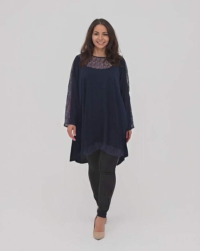 Plus-size μοντέλο σε περιβάλλον στούντιο περπατάει αργά προς την κάμερα φορώντας το προϊόν Κομψή μπλε τουνίκ με πουά plus size
