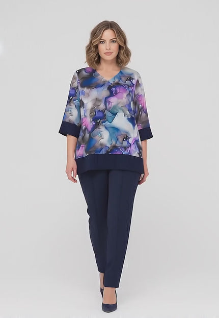 Ένα plus-size γυναικείο μοντέλο σε περιβάλλον στούντιο με ουδέτερο φόντο περπατά αργά προς την κάμερα φορώντας το Σκούρο μπλε επίσημο σετ τουνίκ και παντελόνι plus size