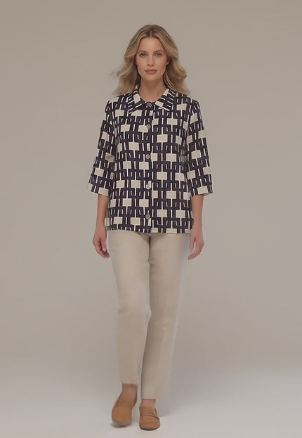 Ένα plus size μοντέλο περπατάει αργά προς την κάμερα σε περιβάλλον στούντιο φορώντας το προϊόν Επίσημο γυναικείο πουκάμισο σε άνετη γραμμή με γεωμετρικό σχέδιο