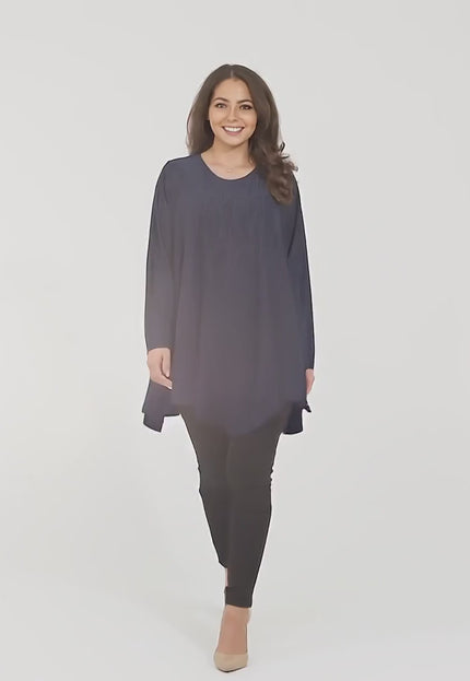 Ένα plus size γυναικείο μοντέλο περπατάει αργά προς την κάμερα σε περιβάλλον στούντιο με ουδέτερο φόντο φορώντας Επίσημη τουνίκ σε σκούρο μπλέ μεγάλα μεγέθη