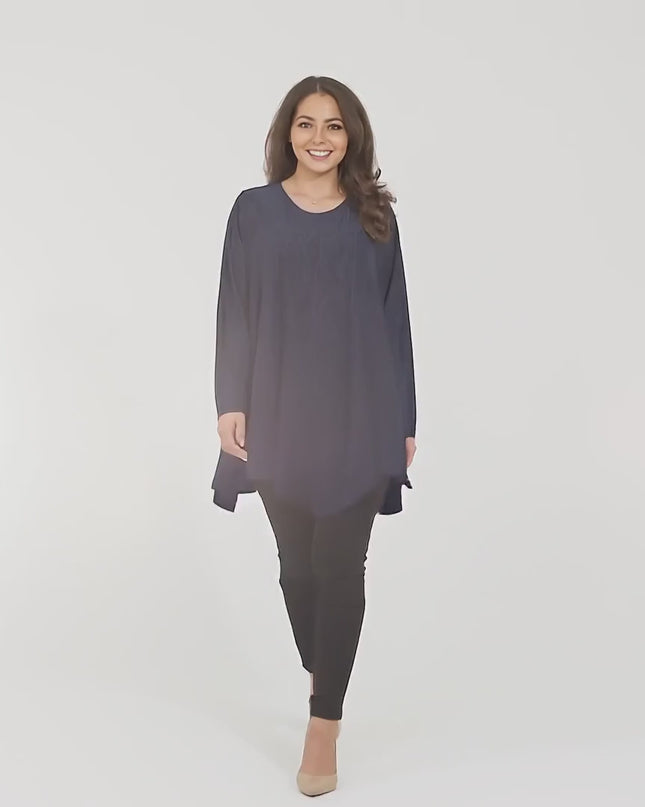 Ένα plus size γυναικείο μοντέλο περπατάει αργά προς την κάμερα σε περιβάλλον στούντιο με ουδέτερο φόντο φορώντας Επίσημη τουνίκ σε σκούρο μπλέ μεγάλα μεγέθη
