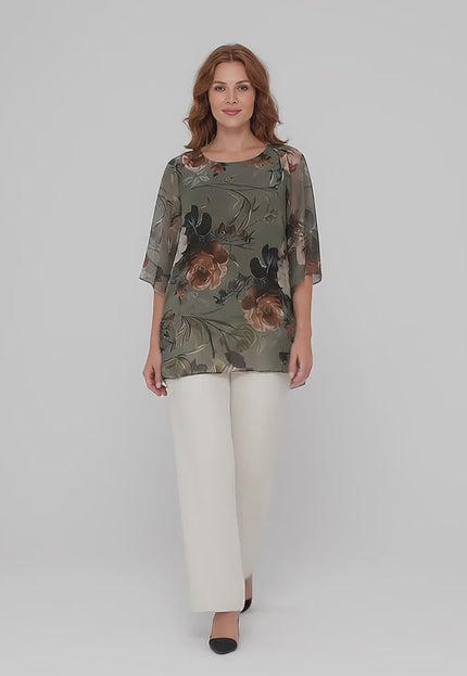 Βίντεο σε περιβάλλον στούντιο όπου ένα plus size μοντέλο περπατάει αργά προς την κάμερα με ουδέτερο φόντο φορώντας το προϊόν Κομψή εβαζέ τουνίκ από σιφόν με φλοράλ σχέδιο σε μεγάλα μεγέθη