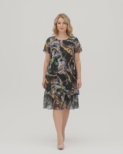 Βίντεο σε στούντιο με ένα μοντέλο να περπατάει αργά προς την κάμερα φορώντας το Επίσημο κλος φόρεμα σε μεγάλα μεγέθη από πολύχρωμο σιφόν