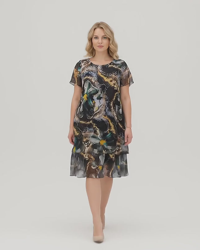 Βίντεο σε στούντιο με ένα μοντέλο να περπατάει αργά προς την κάμερα φορώντας το Επίσημο κλος φόρεμα σε μεγάλα μεγέθη από πολύχρωμο σιφόν