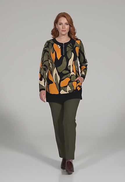 Σε περιβάλλον στούντιο, ένα plus-size μοντέλο περπατάει αργά προς την κάμερα ενώ φοράει το προϊόν Επίσημη εβαζέ τουνίκ μεγάλα μεγέθη με φερμουάρ και πολύχρωμο σχέδιο