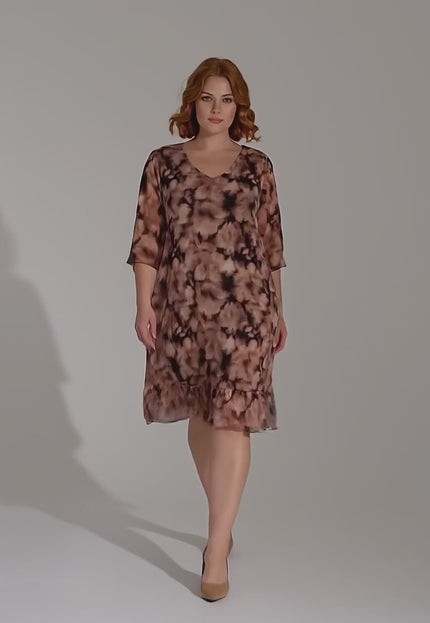 Ένα plus-size μοντέλο περπατάει αργά προς την κάμερα σε περιβάλλον στούντιο με ουδέτερο φόντο φορώντας το Επίσημο φόρεμα μεγάλα μεγέθη από αέρινο σιφόν με ντεγκραντέ σχέδιο