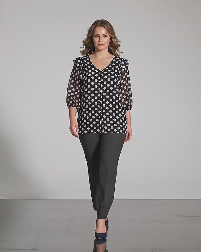 Βίντεο παρουσίασης σε στούντιο με ουδέτερο φόντο όπου ένα γυναικείο μοντέλο περπατάει αργά προς την κάμερα φορώντας το προϊόν Επίσημη γυναικεία σκούρα μπλε τουνίκ με λευκό πουά σε μεγάλα μεγέθη