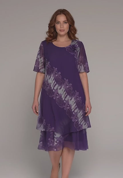 Γυναικείο plus-size μοντέλο περπατάει αργά προς την κάμερα σε περιβάλλον στούντιο με ουδέτερο φόντο, φορώντας το προϊόν Επίσημο μωβ φόρεμα μεγάλα μεγέθη με σιφόν