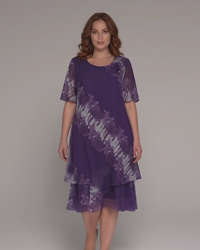 Γυναικείο plus-size μοντέλο περπατάει αργά προς την κάμερα σε περιβάλλον στούντιο με ουδέτερο φόντο, φορώντας το προϊόν Επίσημο μωβ φόρεμα μεγάλα μεγέθη με σιφόν