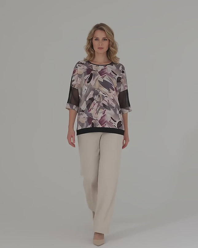 Βίντεο παρουσίασης σε στούντιο με ουδέτερο φόντο όπου ένα μοντέλο περπατάει αργά προς την κάμερα φορώντας το προϊόν Επίσημη τουνίκ plus size με δίχτυ και αφηρημένο μοτίβο