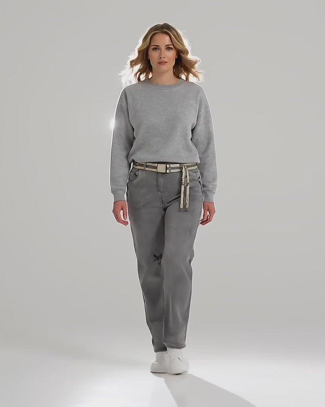 Μία plus-size γυναίκα μοντέλο περπατά αργά προς την κάμερα σε περιβάλλον στούντιο με ουδέτερο φόντο φορώντας το προϊόν Γκρι καθημερινό τζιν παντελόνι μεγάλα μεγέθη σε ίσια γραμμή με λάστιχο