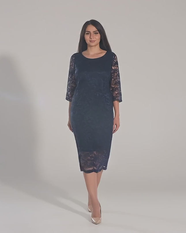 Ένα plus-size μοντέλο περπατάει αργά προς την κάμερα σε περιβάλλον στούντιο με ουδέτερο φόντο παρουσιάζοντας και φορώντας το προϊόν Σκούρο Μπλε Φόρεμα- Στρογγυλή Λαιμόκοψη - Κάτω από το Γόνατο - Άνοιξη-Καλοκαίρι