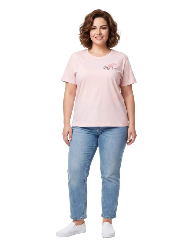 Ολόσωμη λήψη με ροζ βαμβακερό γυναικείο t-shirt με στάμπα σε μεγάλα μεγέθη, συνδυασμένο με τζιν παντελόνι και λευκά slip-on sneakers.