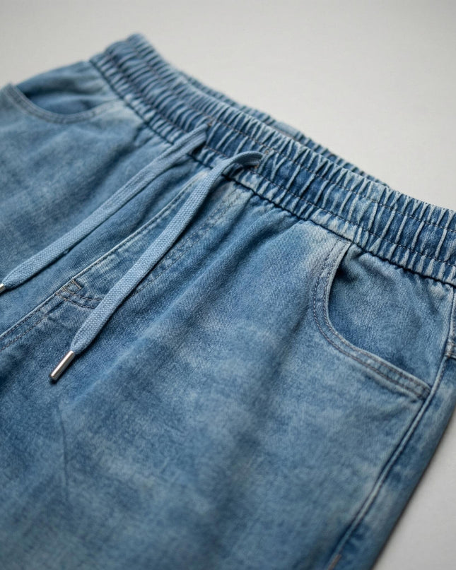 Детайл отблизо на талията на сини макси дамски дънки, показващ еластичния колан с връзки и текстурата на материята от тенсел и памук.