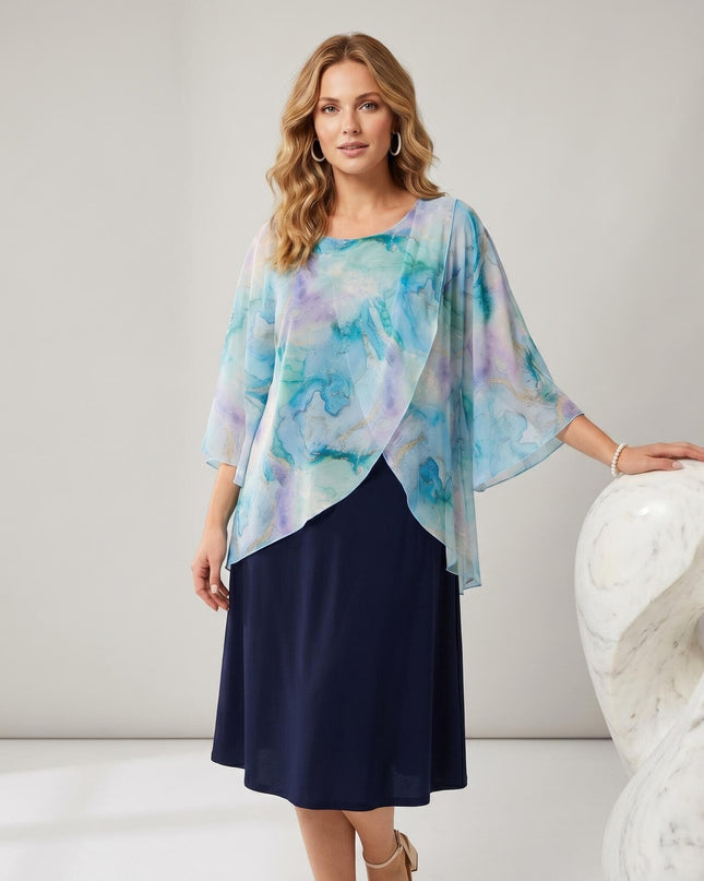 Σκούρο μπλε επίσημο φόρεμα σε μεγάλα μεγέθη, με αέρινη κάπα από σιφόν και αφηρημένο print. Λήψη 3/4 σε ανοιχτόχρωμο φόντο, που αναδεικνύει την εβαζέ γραμμή.