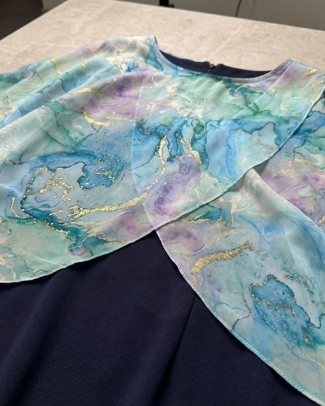 Κοντινή λεπτομέρεια από σκούρο μπλε επίσημο φόρεμα σε μεγάλα μεγέθη, που αναδεικνύει το αέρινο σιφόν με το αφηρημένο ακουαρέλ print.