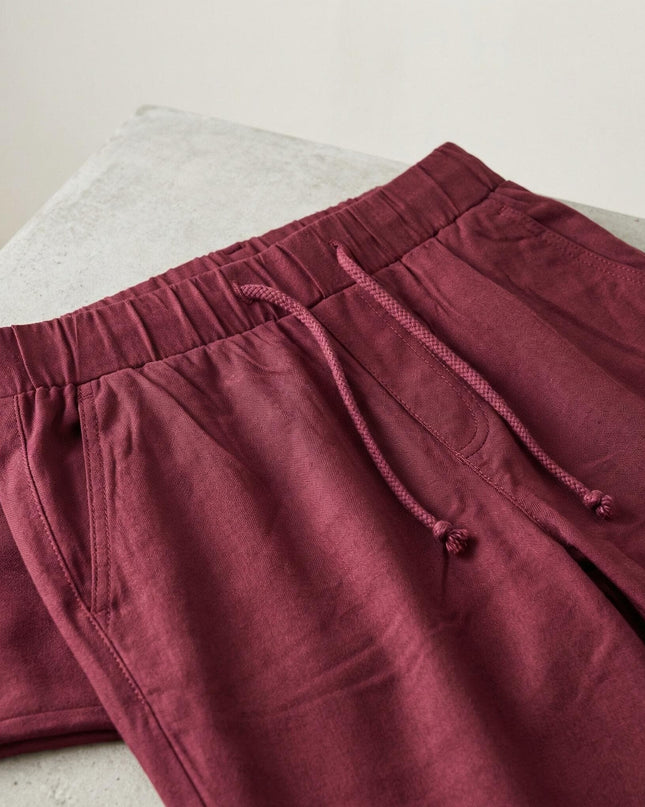 Κοντινή λήψη σε μπορντό γυναικείο παντελόνι μεγάλα μεγέθη, με έμφαση στην ελαστική ζώνη μέσης με κορδόνι και τις πλαϊνές τσέπες.