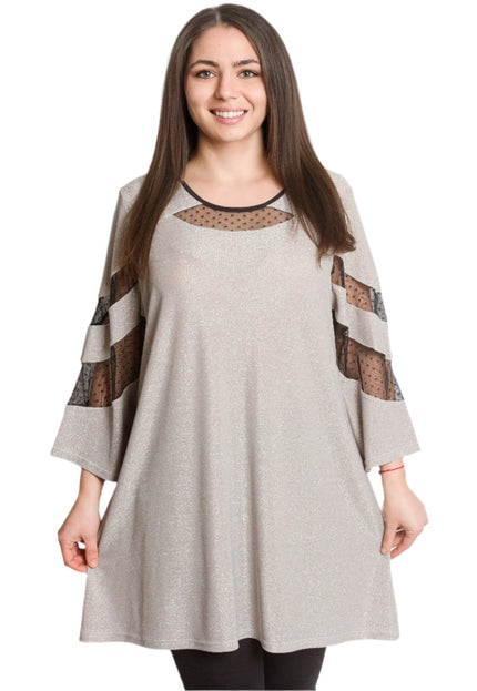 Γυναίκα φοράει λαμπερή μπεζ τουνίκ με μαύρες λεπτομέρειες από πουά τούλι στο ντεκολτέ και στα μανίκια.