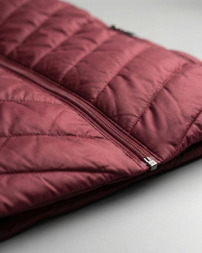 Детайл отблизо на зимно макси яке в бордо, показващ вълнообразното капитониране на материята и качествения преден цип.