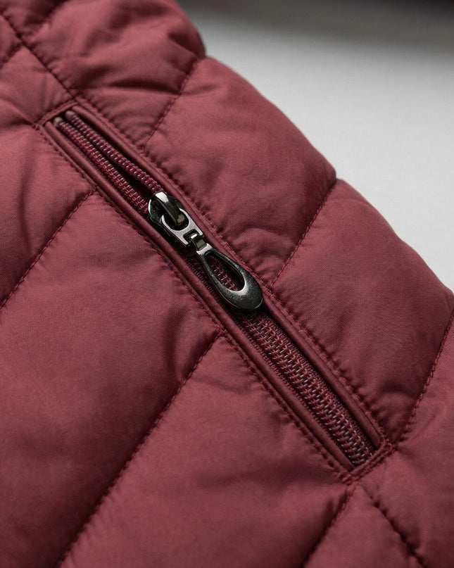 Детайл отблизо на джоб с цип върху зимно макси яке в бордо, показващ капитонираната полиестерна материя и качествената изработка.